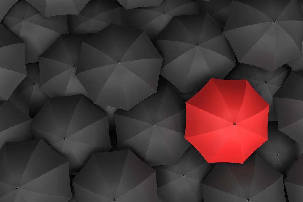 Schwarze Regenschirme und ein roter Regenschirm